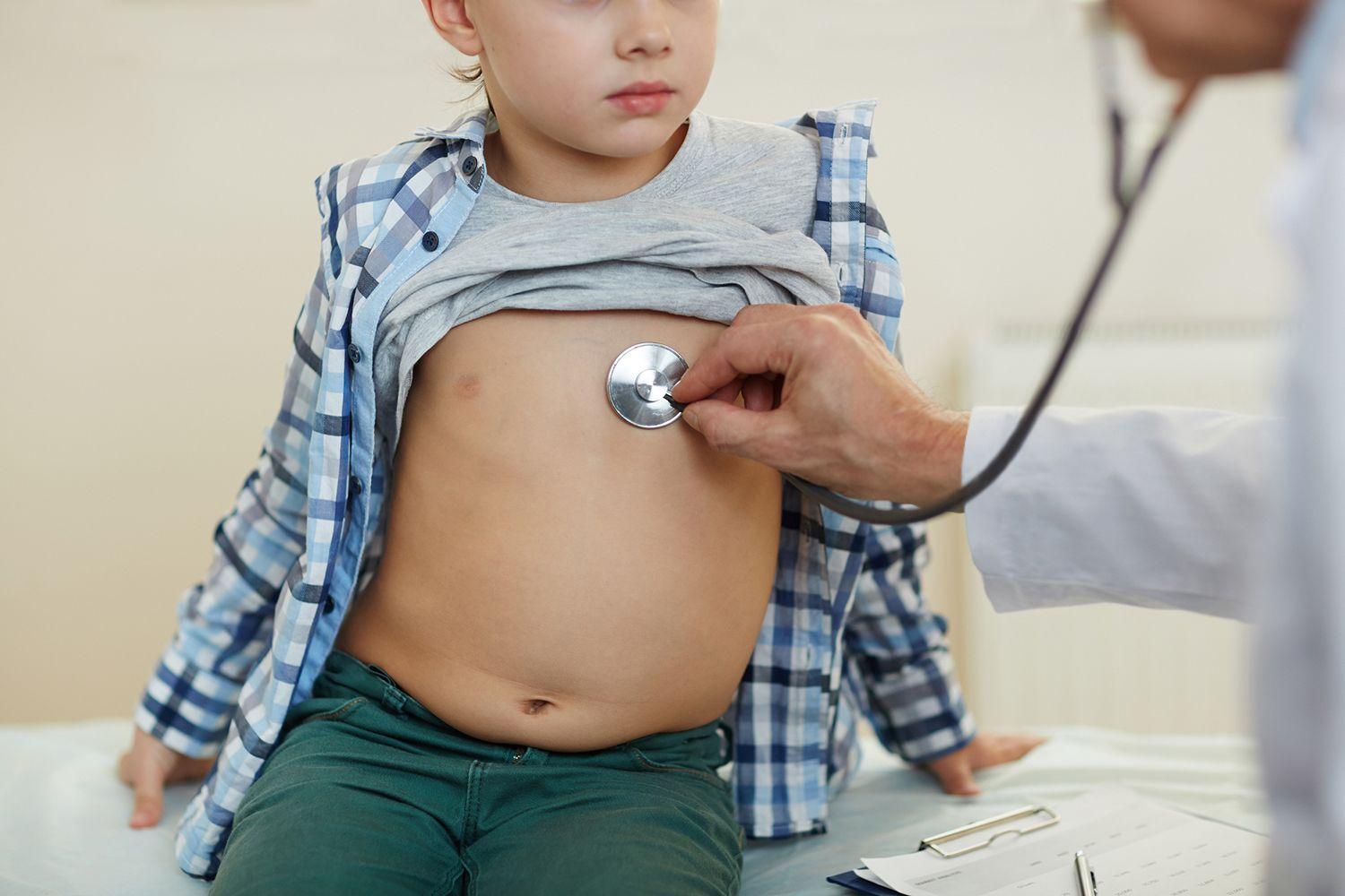 En doktor lyssnar på en liten pojkes hjärta.