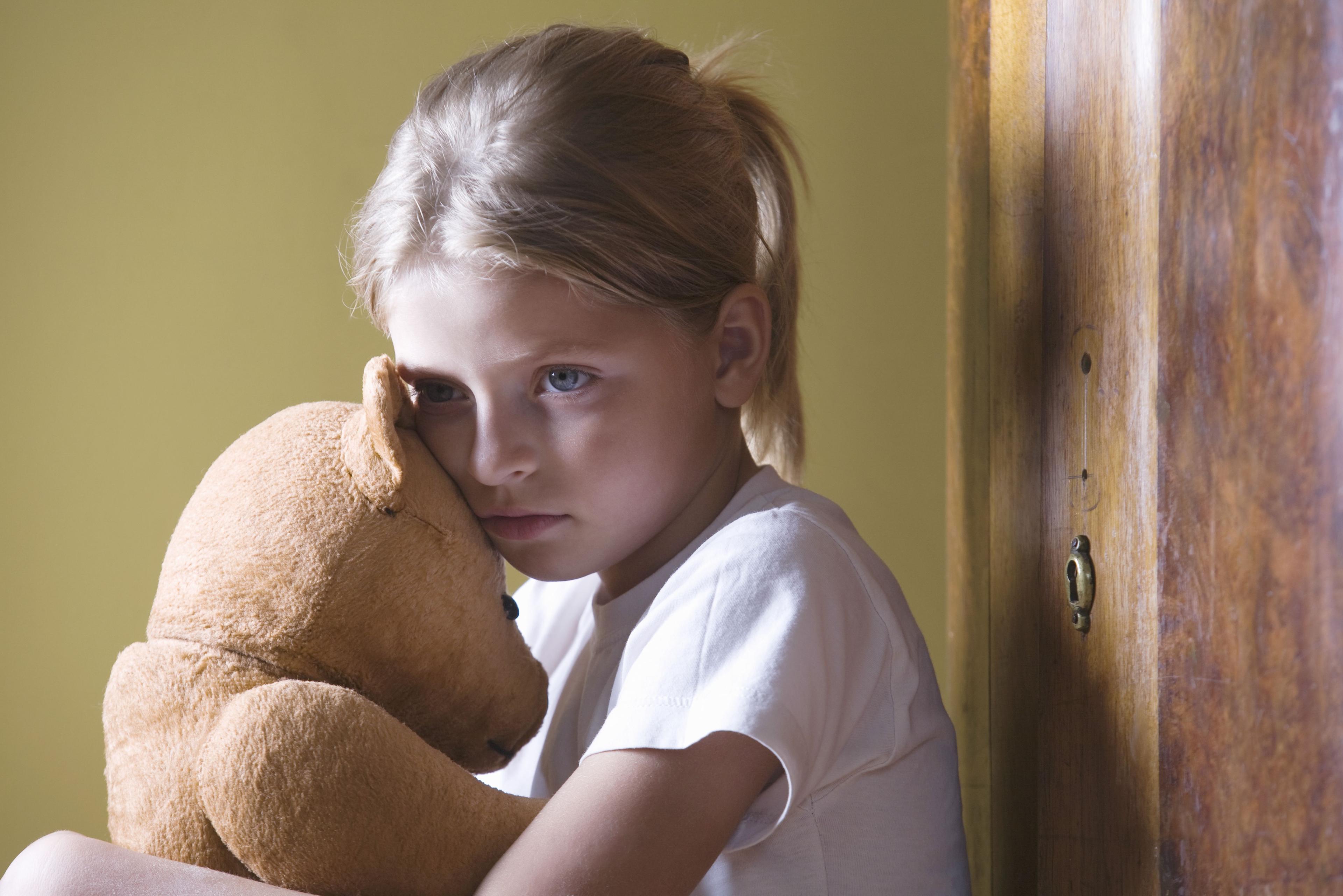 Sad girl is holding a teddy bear.