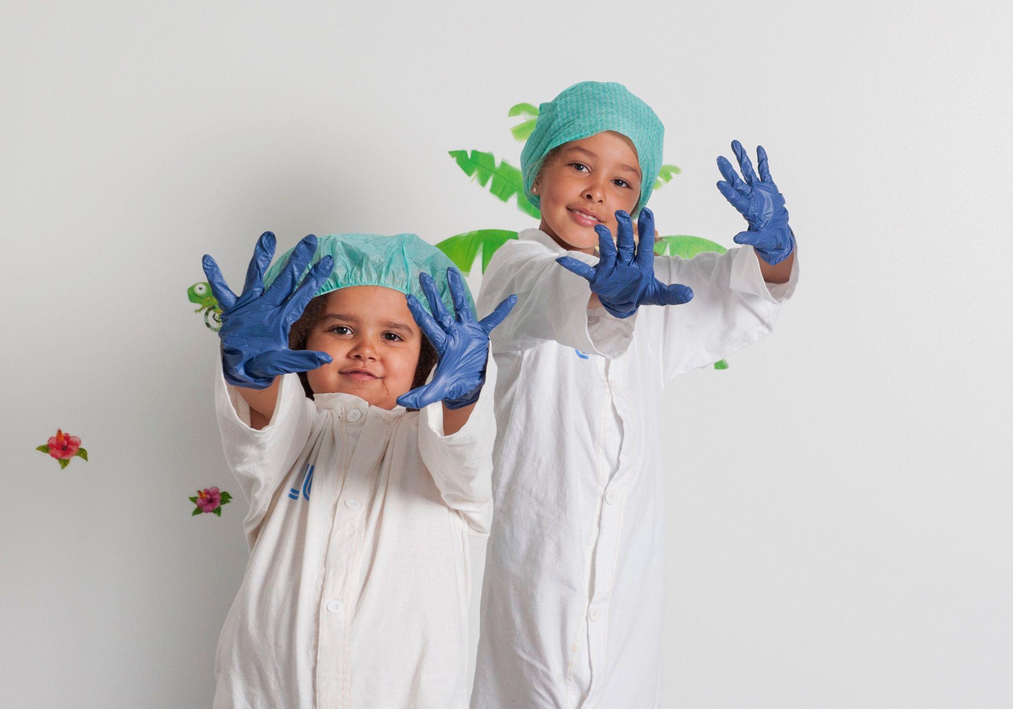 Två flickor i gröna operationsmössor och blå operationshandskar.