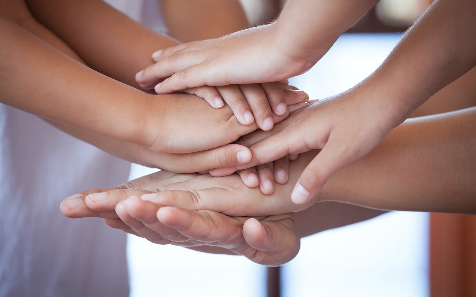 Several people of different ages who put their hands on each other's hands