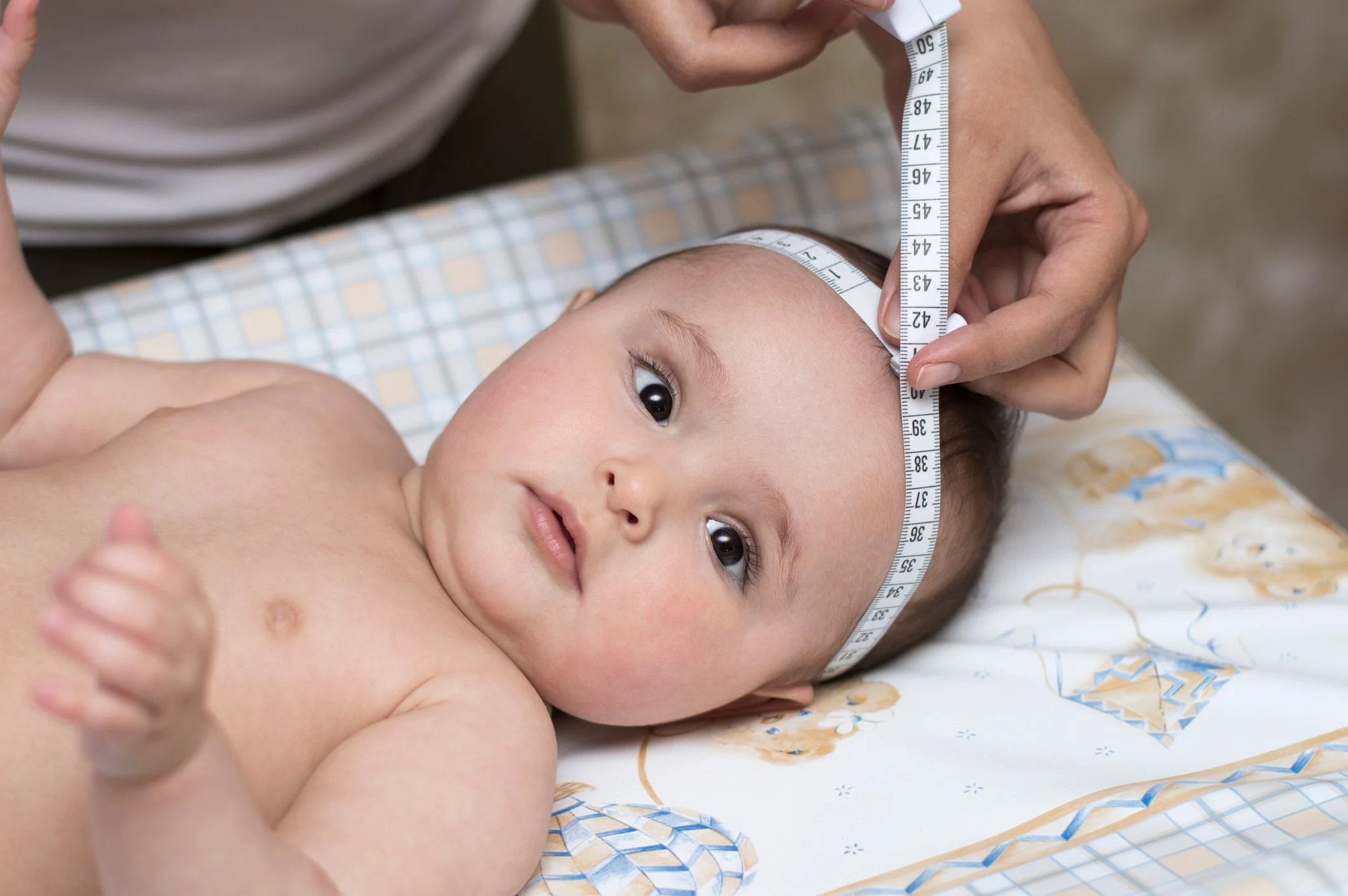 Mätning av omkretsen på huvudet med ett måttband på en bebis.