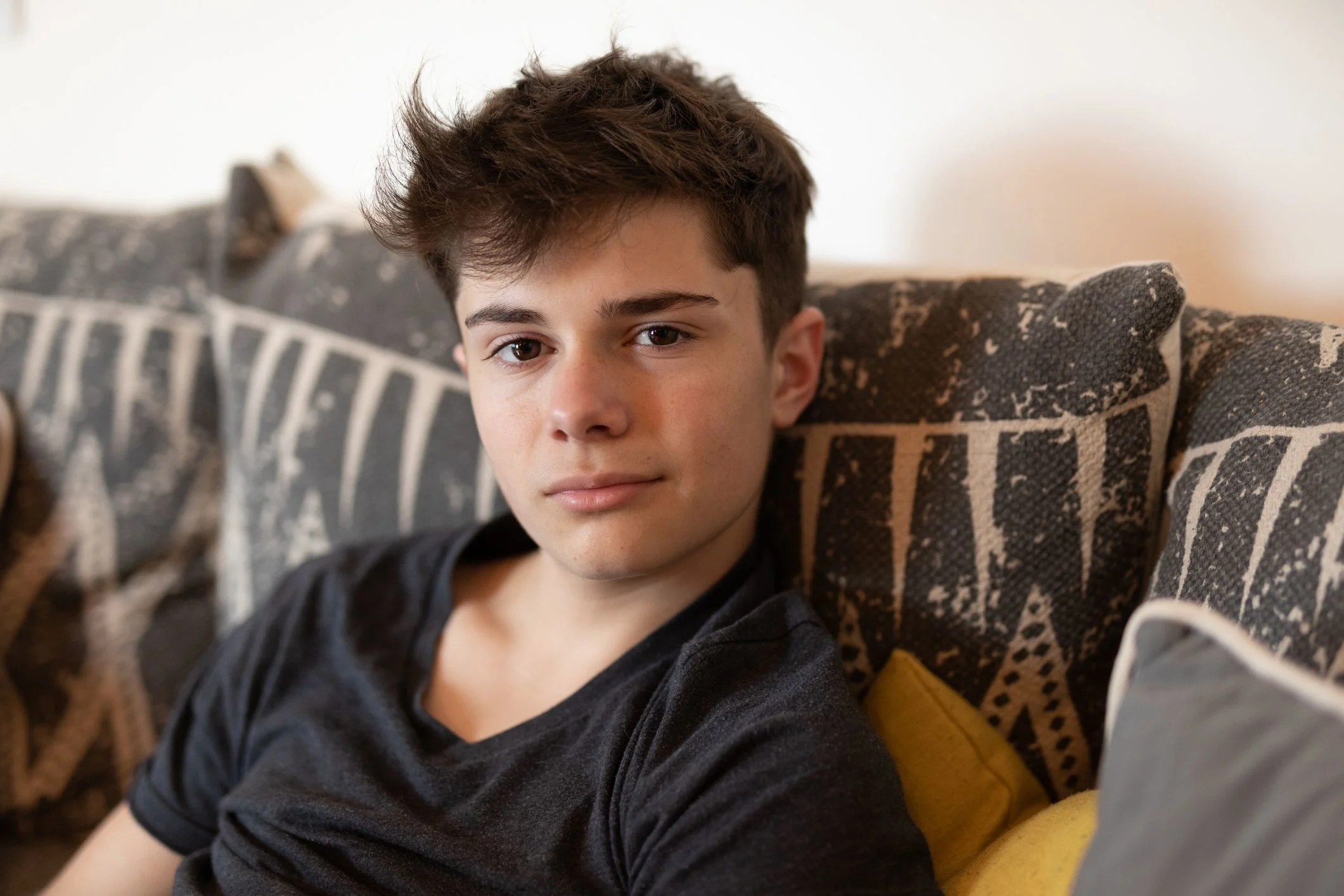 Tonårspojke med mörkt hår tittar in i kameran.