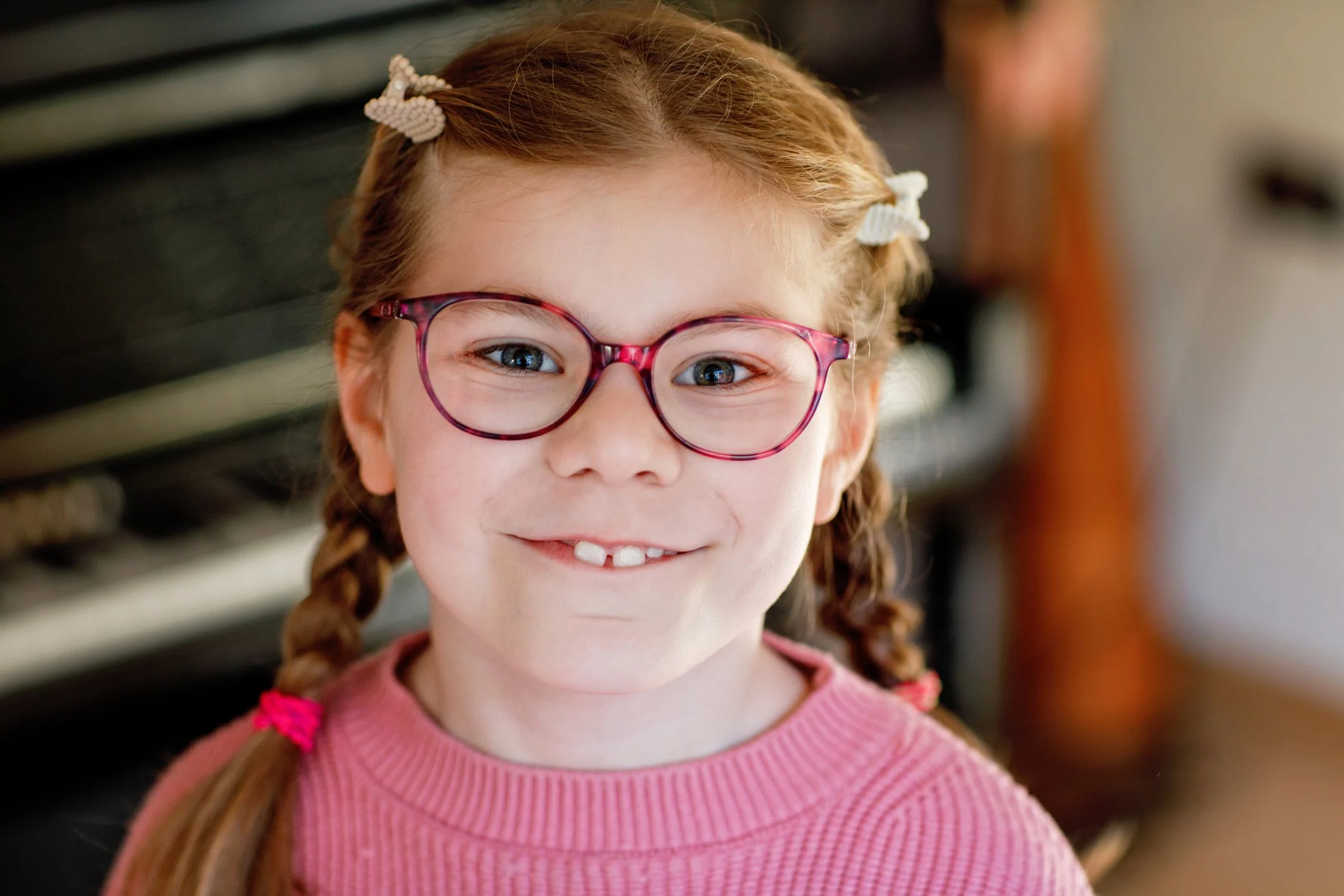 Flicka med flätor och röda glasögon tittar in i kameran.