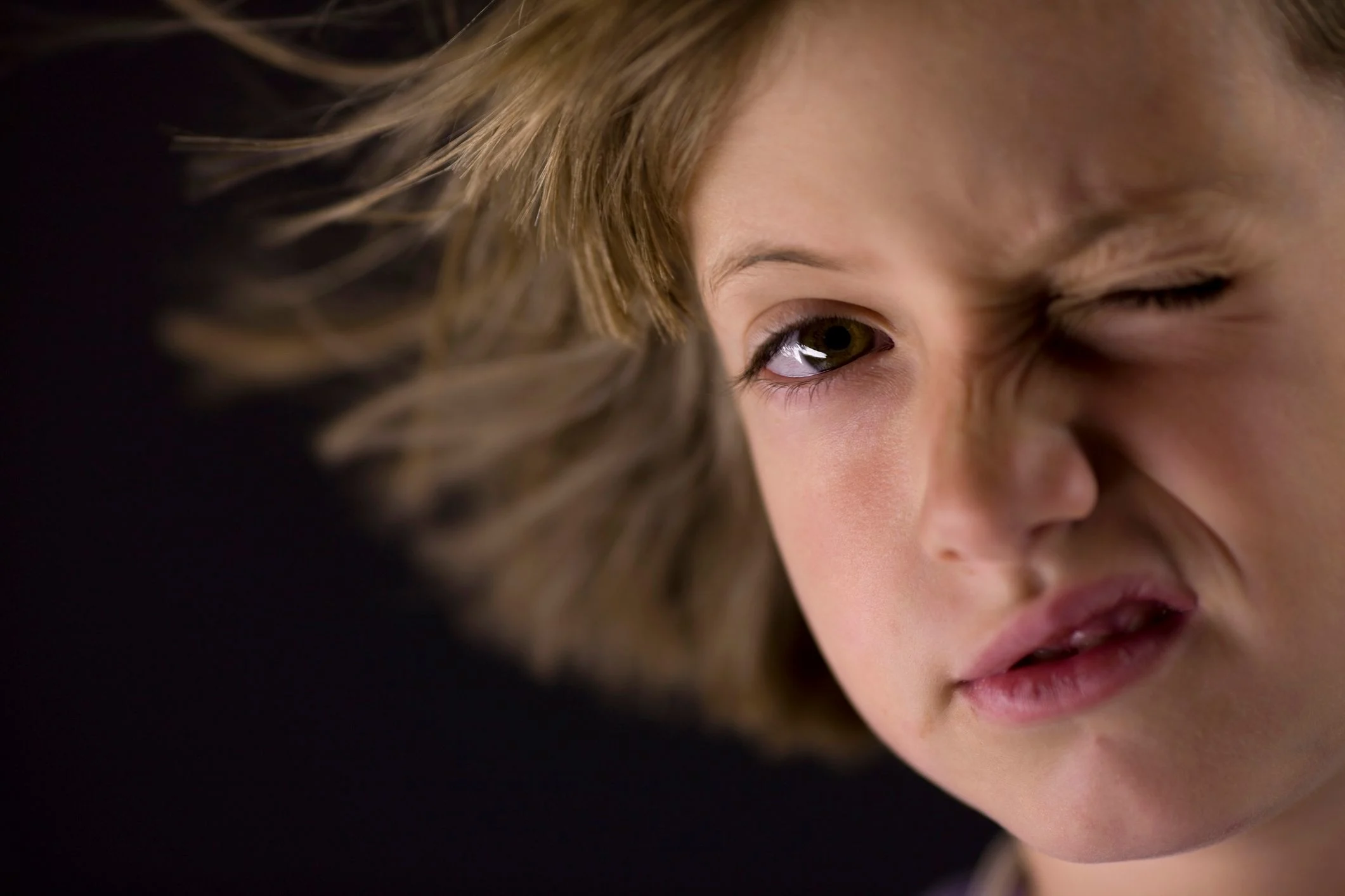 Pojke blinkar med ena ögat när han tittar in i kameran.