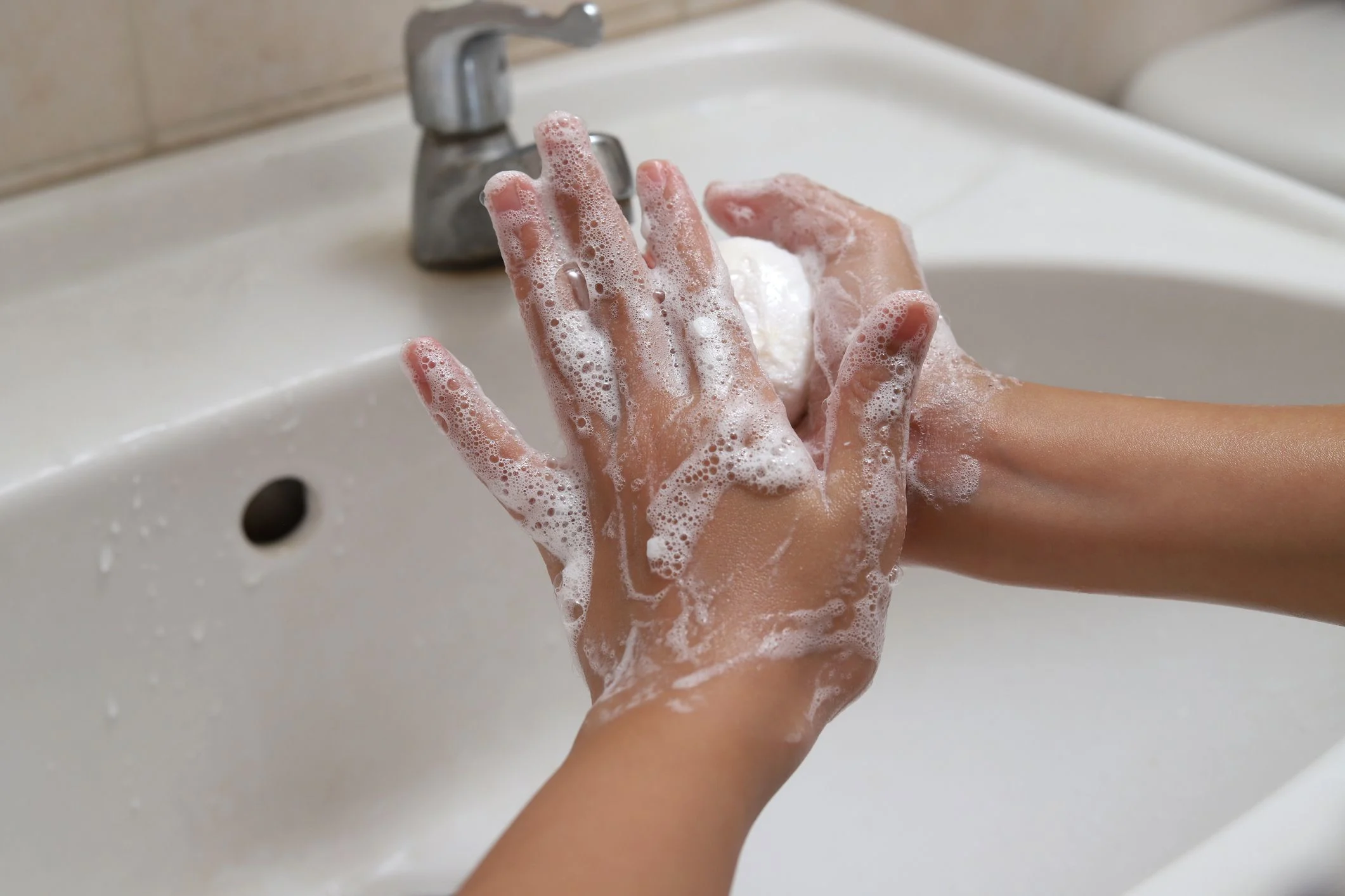 En flicka tvättar händerna. Det löddrar mycket från tvålen.