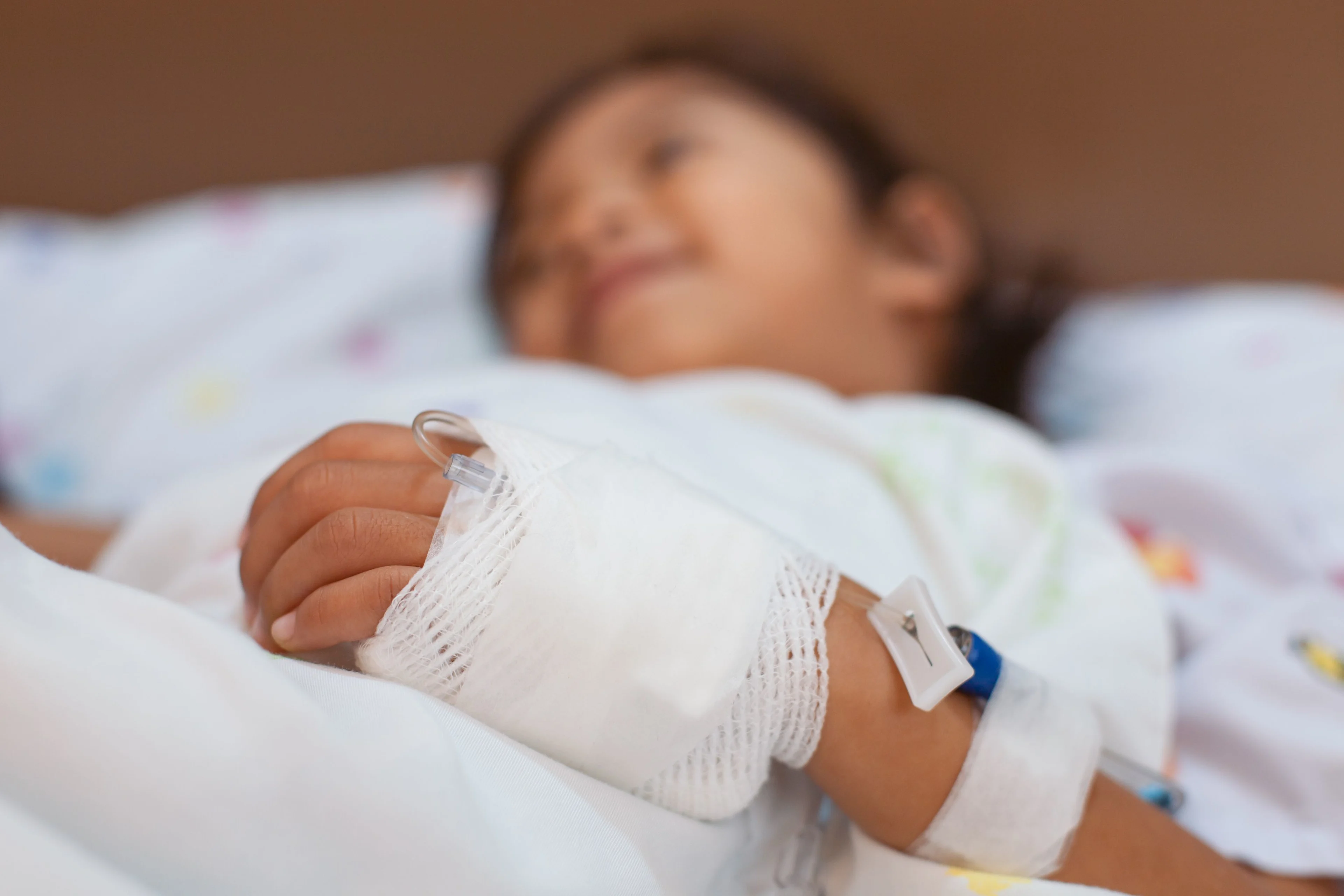 Flicka i sjukhussäng. Bandage över en infart på handleden.