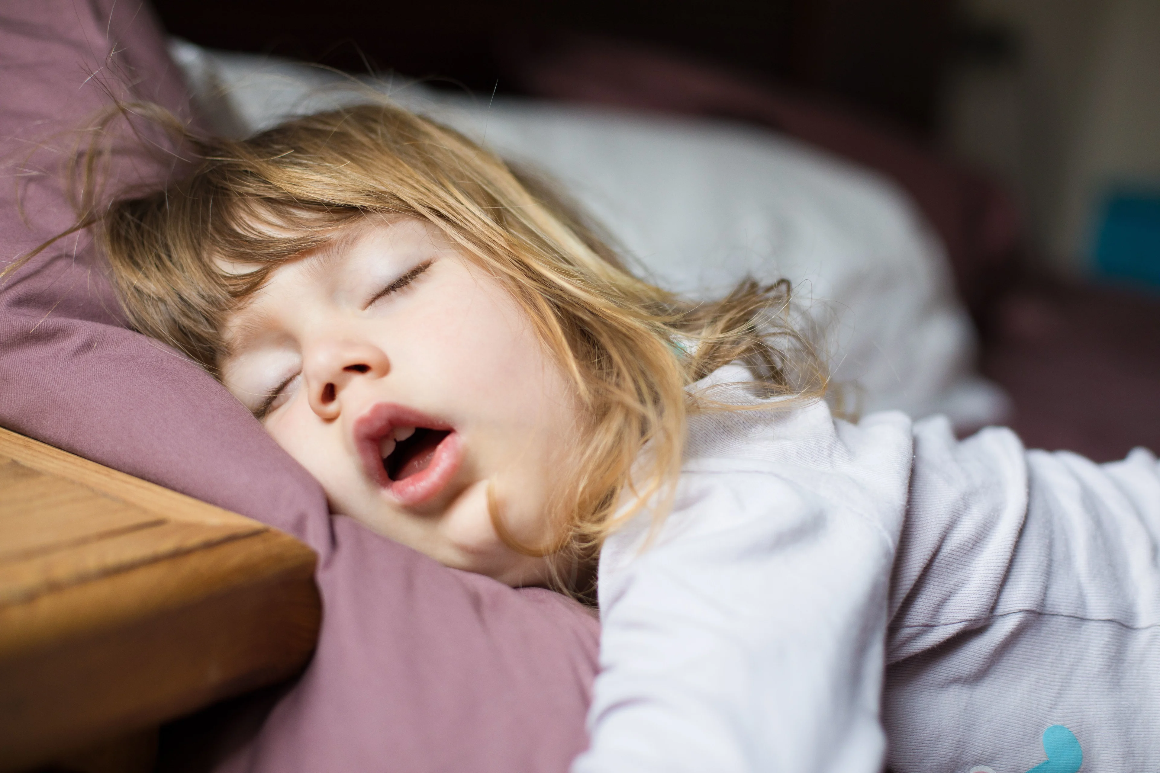 Flicka sover med öppen mun.