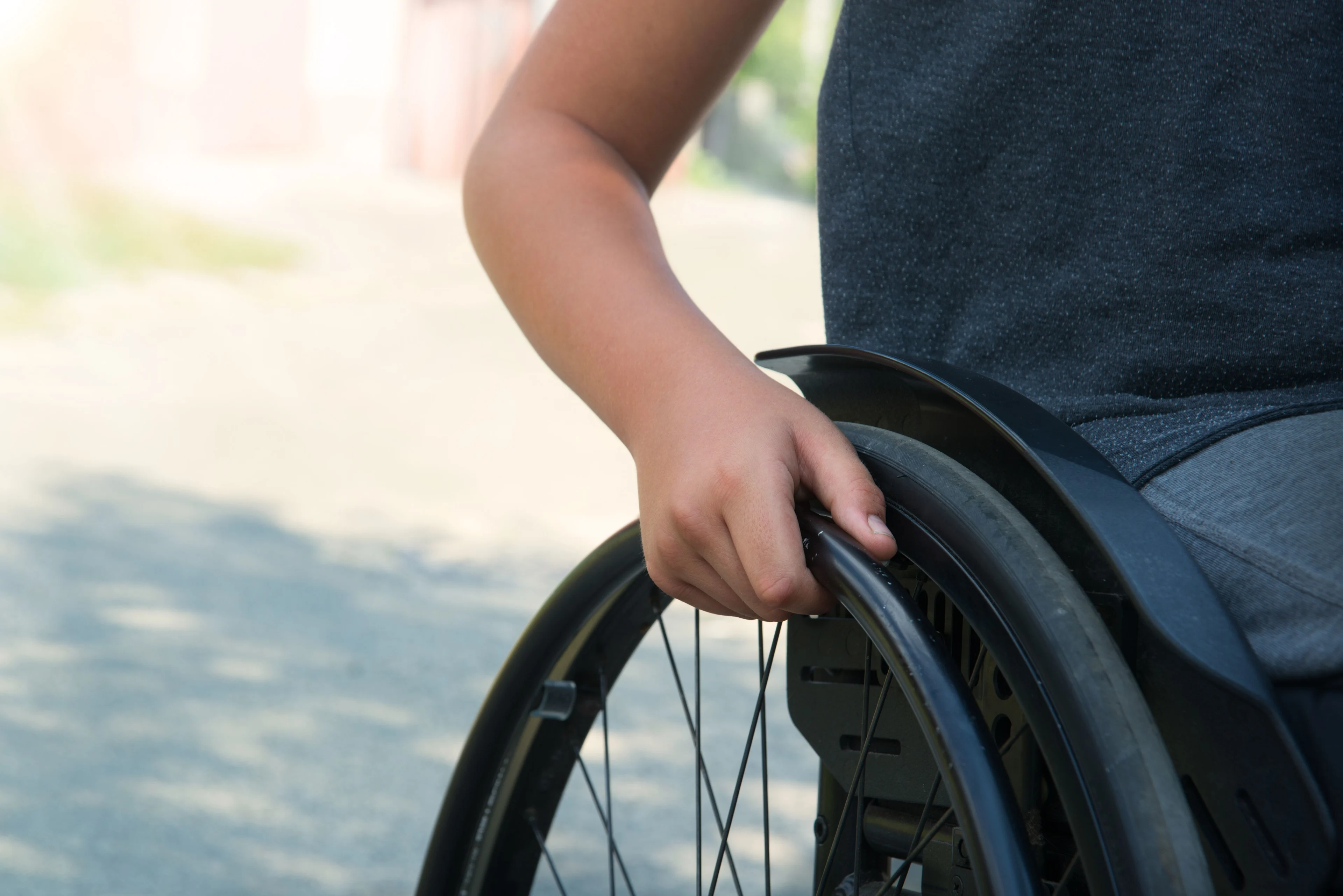 Närbild på armen på en pojke som kör sin rullstol.