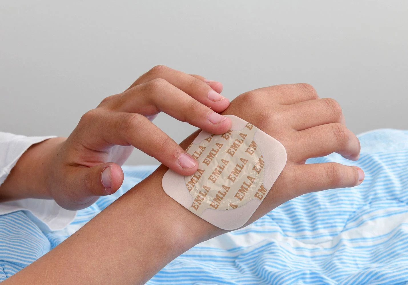 Flicka känner på bedövningsplåstret hon har på höger handrygg.