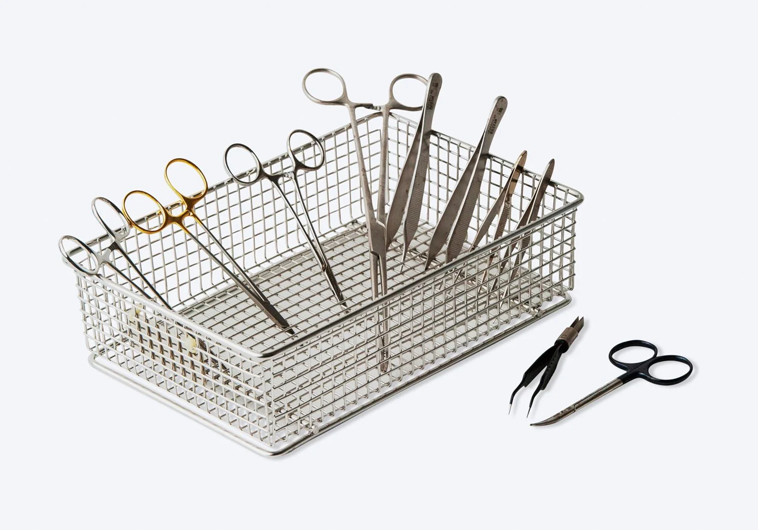 Låda av metall med flera olika silver- och guldfärgade operationsredskap.