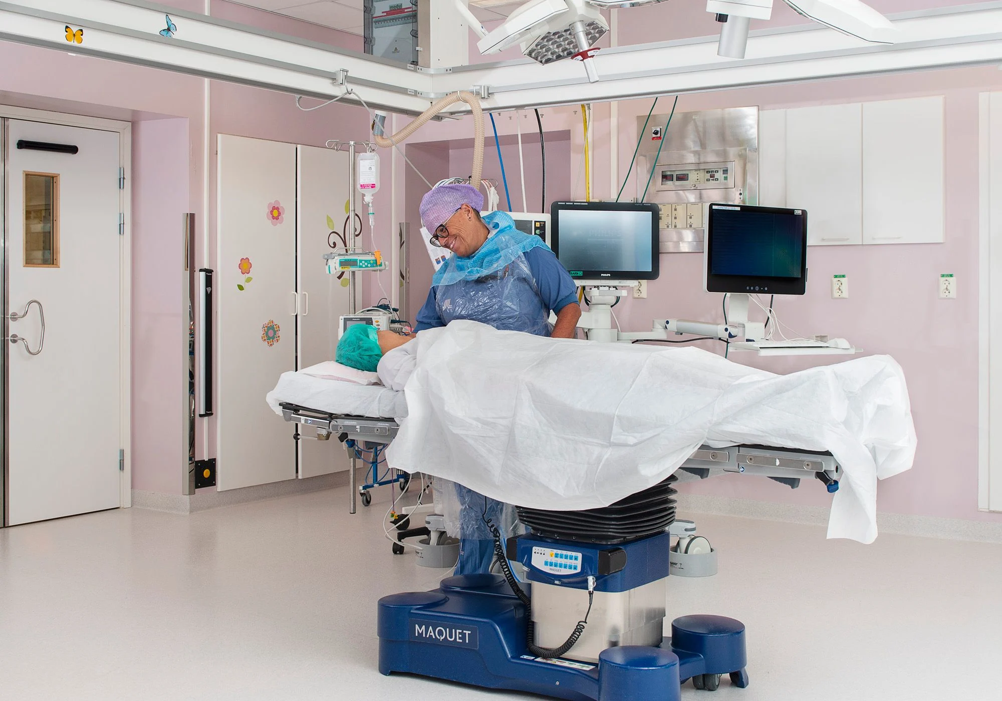 Flicka ligger på operationsbord. Sjuksköterska står bredvid bordet och pratar med flickan.