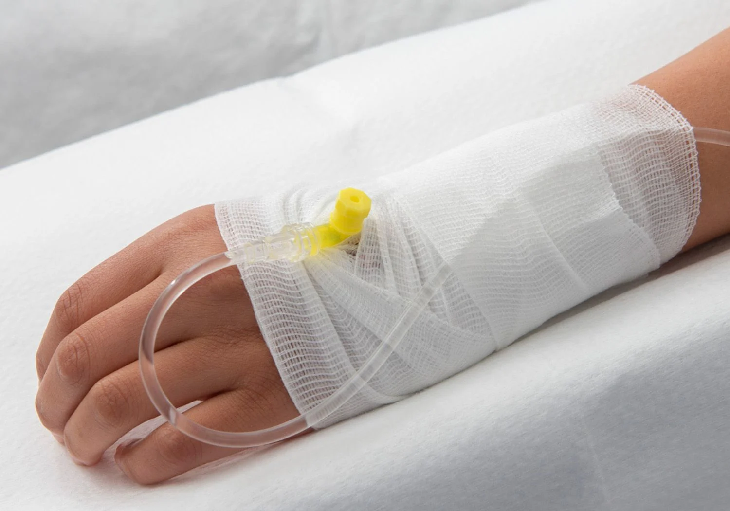 Hand med plastslang och dropp. En linda runt om handen.