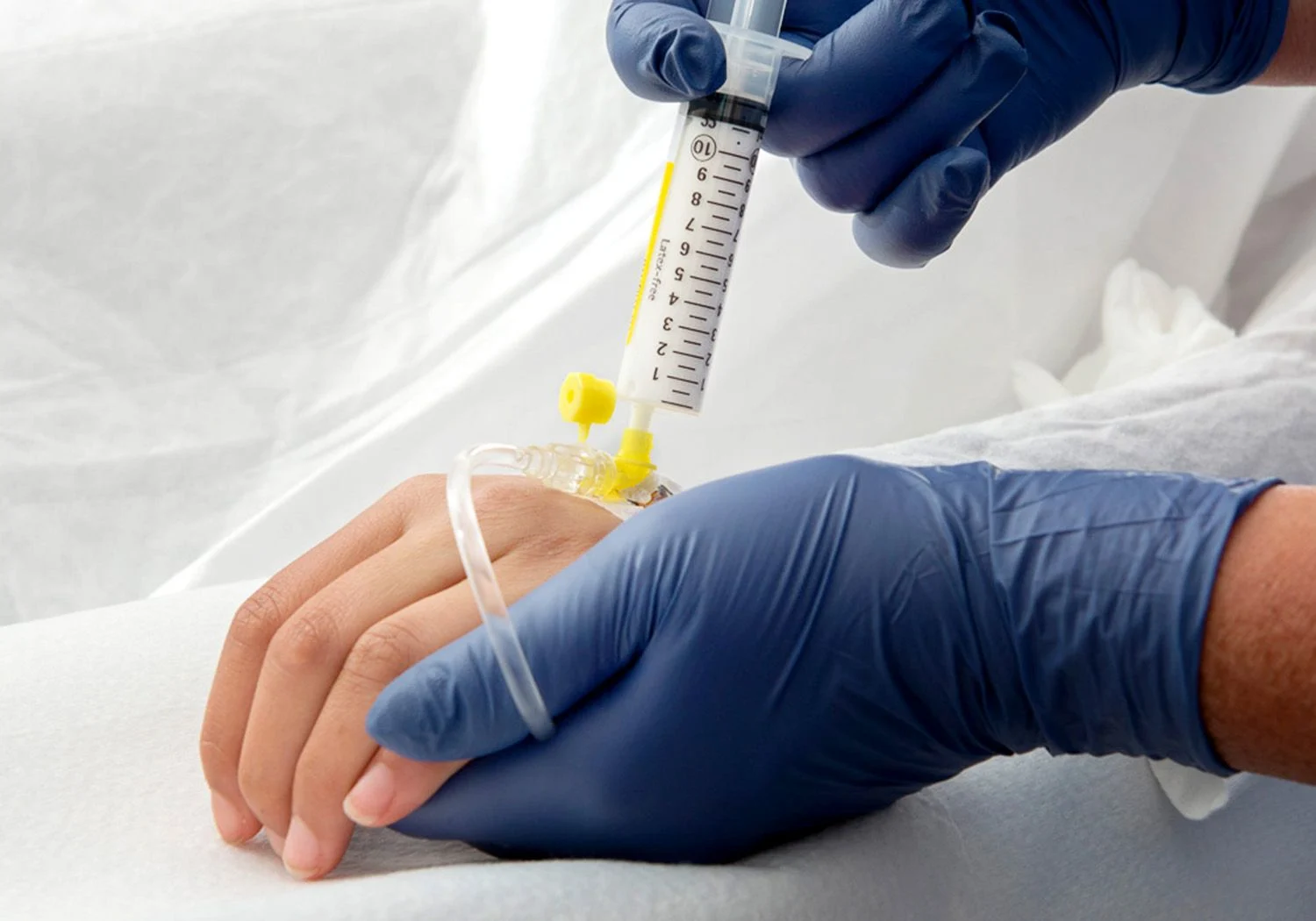 Sjuksköterska ger medicin i en plastslang.