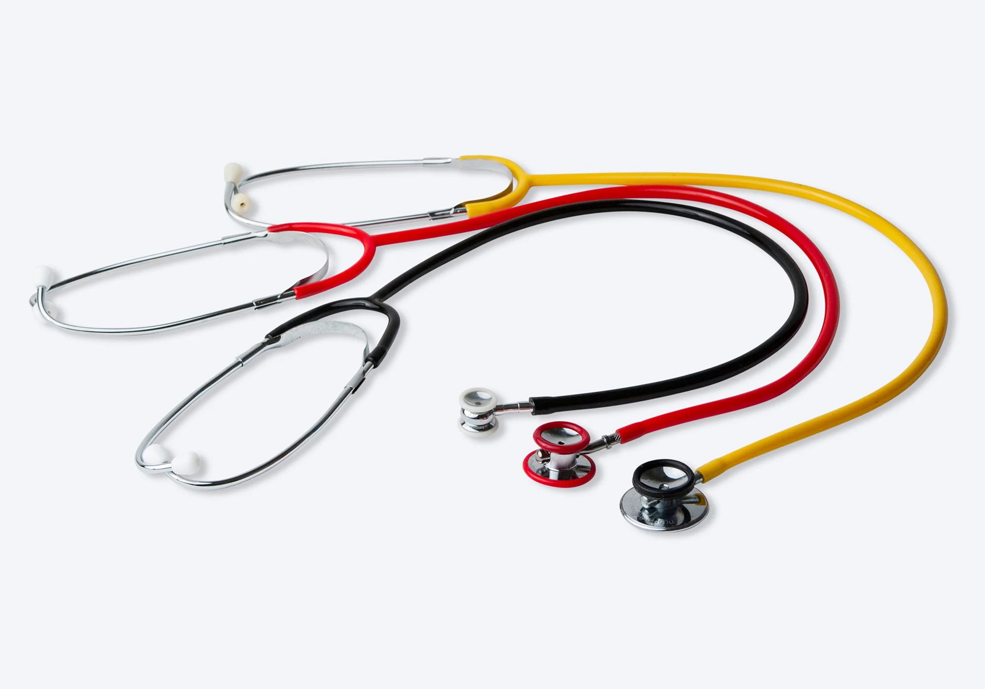 Ett rött, ett gult och ett svart stetoskop ligger bredvid varann.