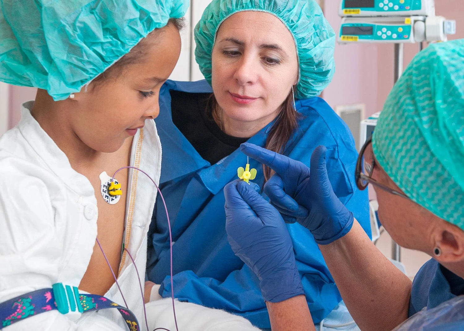 Sjuksköterska visar en flicka plastslangen när nålen har tagits bort.