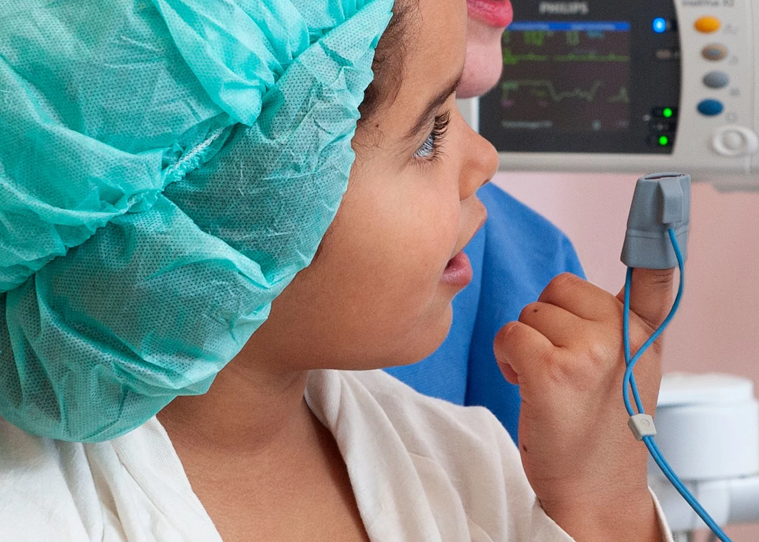 Flicka med syremätare på fingret tittar på en övervakningsskärm.