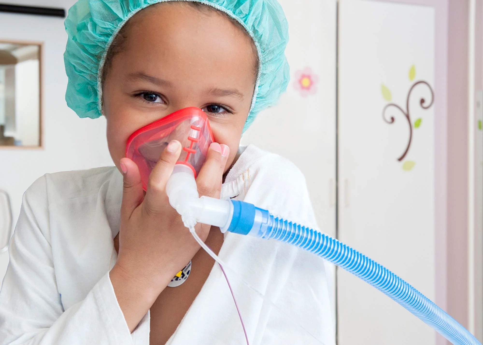 Flicka håller en syretratt över mun och näsa.