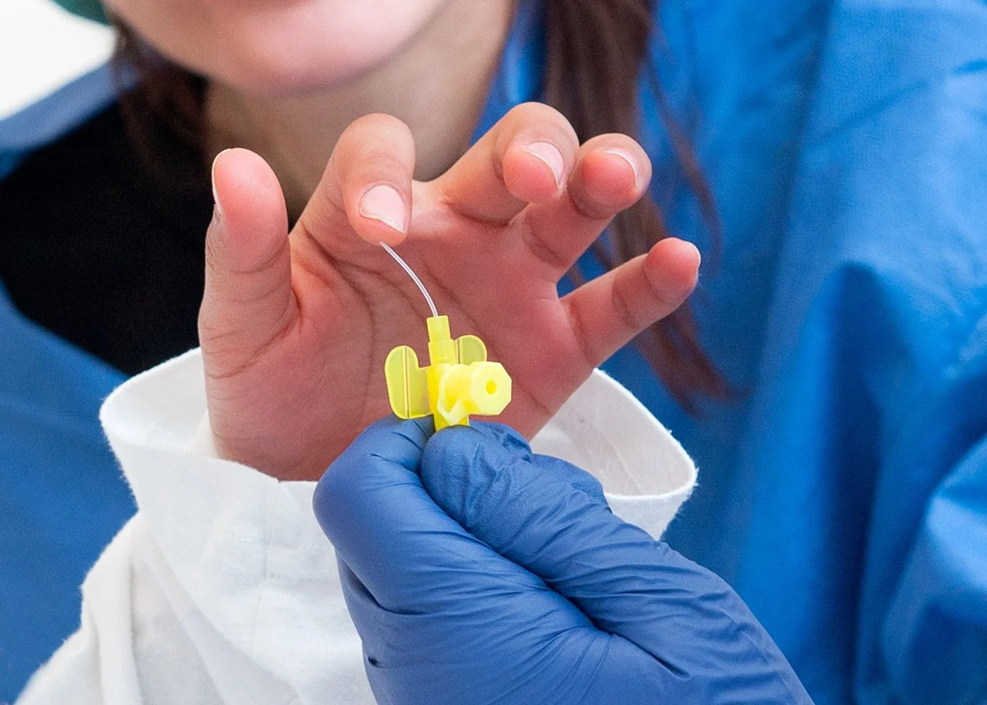 Flicka känner på den mjuka plastslangen när nålen har tagits bort.